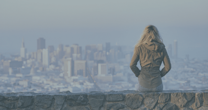 Frau sitzt auf Mauer